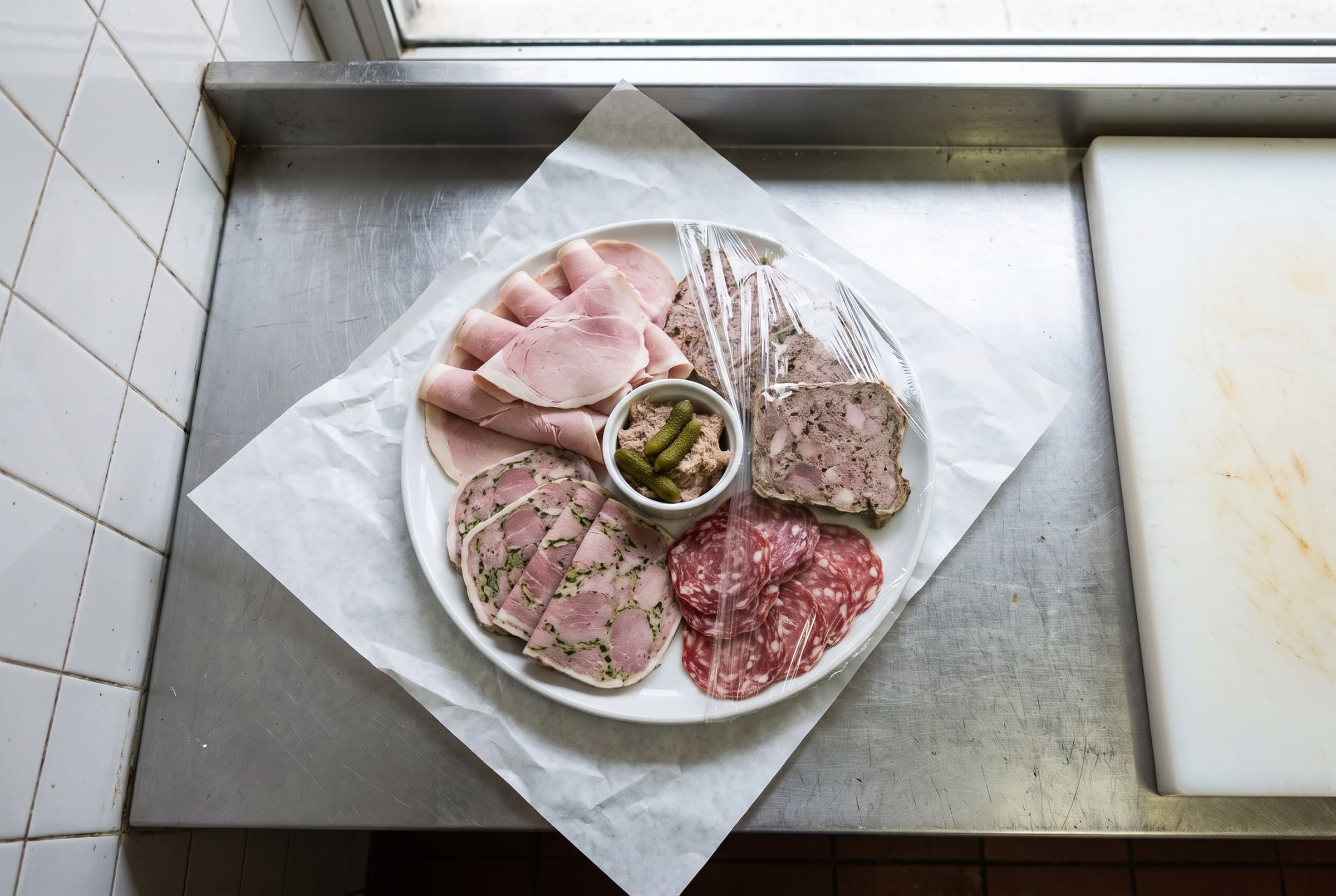 Un plateau de charcuterie maison : jambon, terrine, saucisson et cornichons