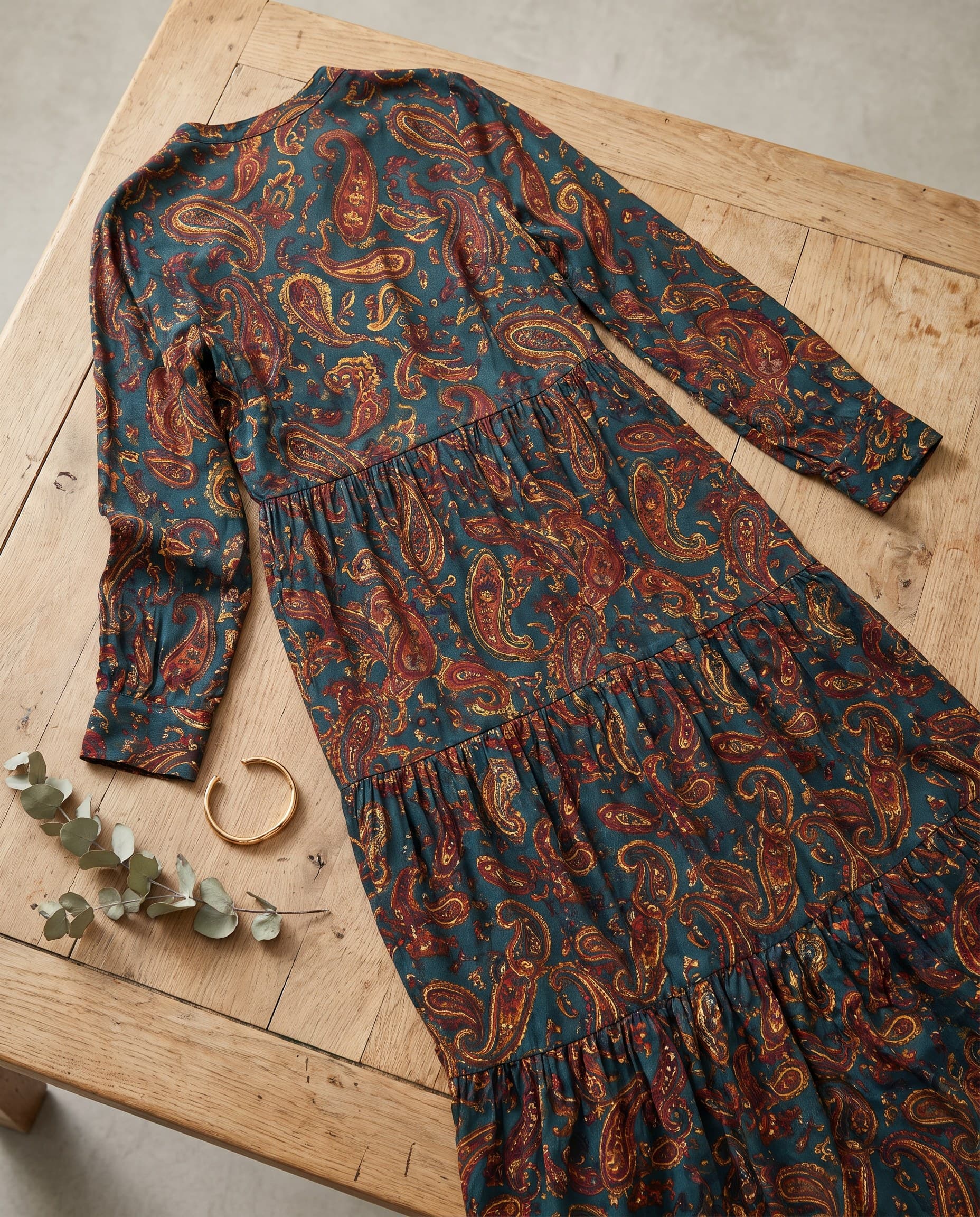 Une robe longue paisley posée sur une table en bois