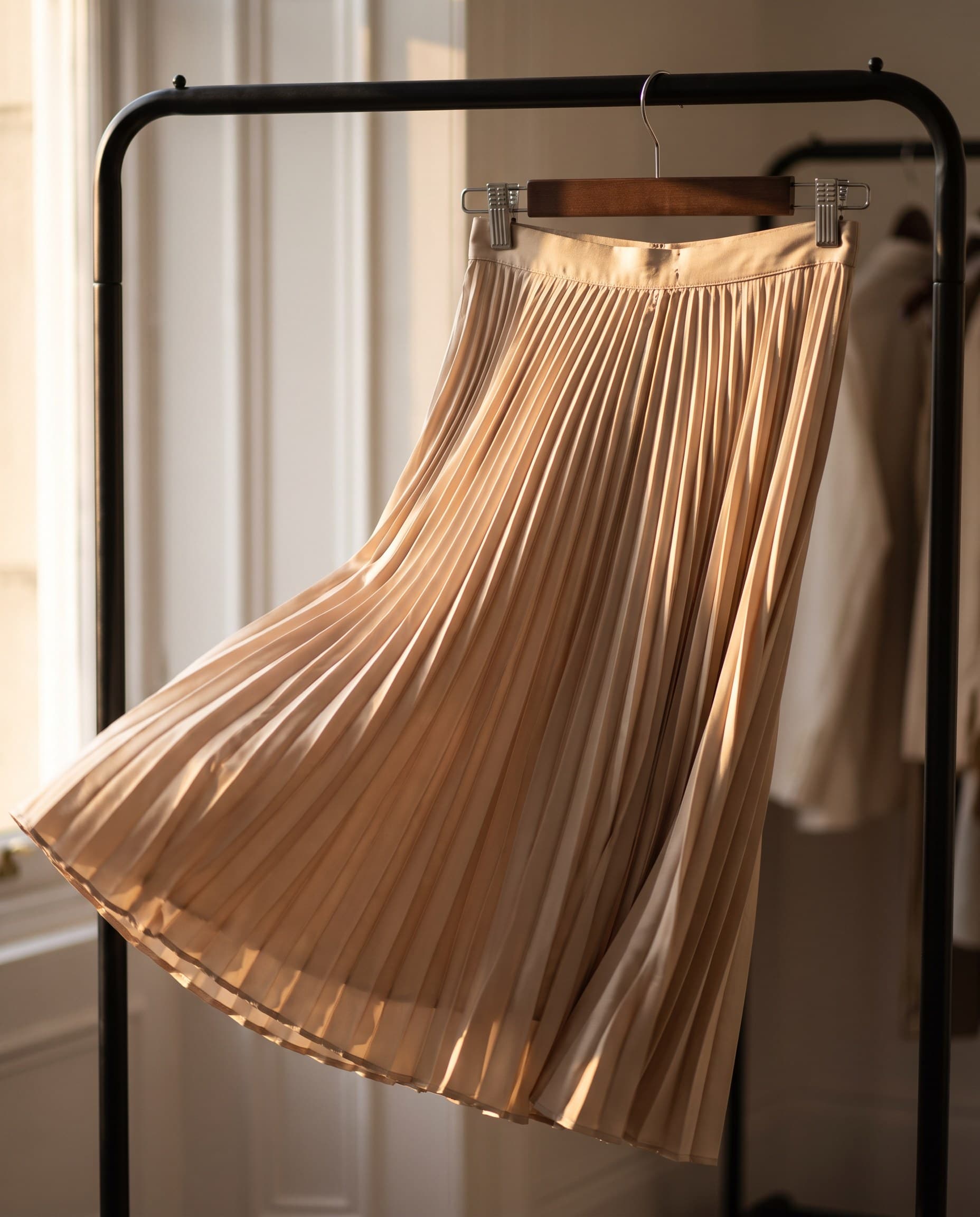 Une jupe plissée en satin champagne sur son cintre
