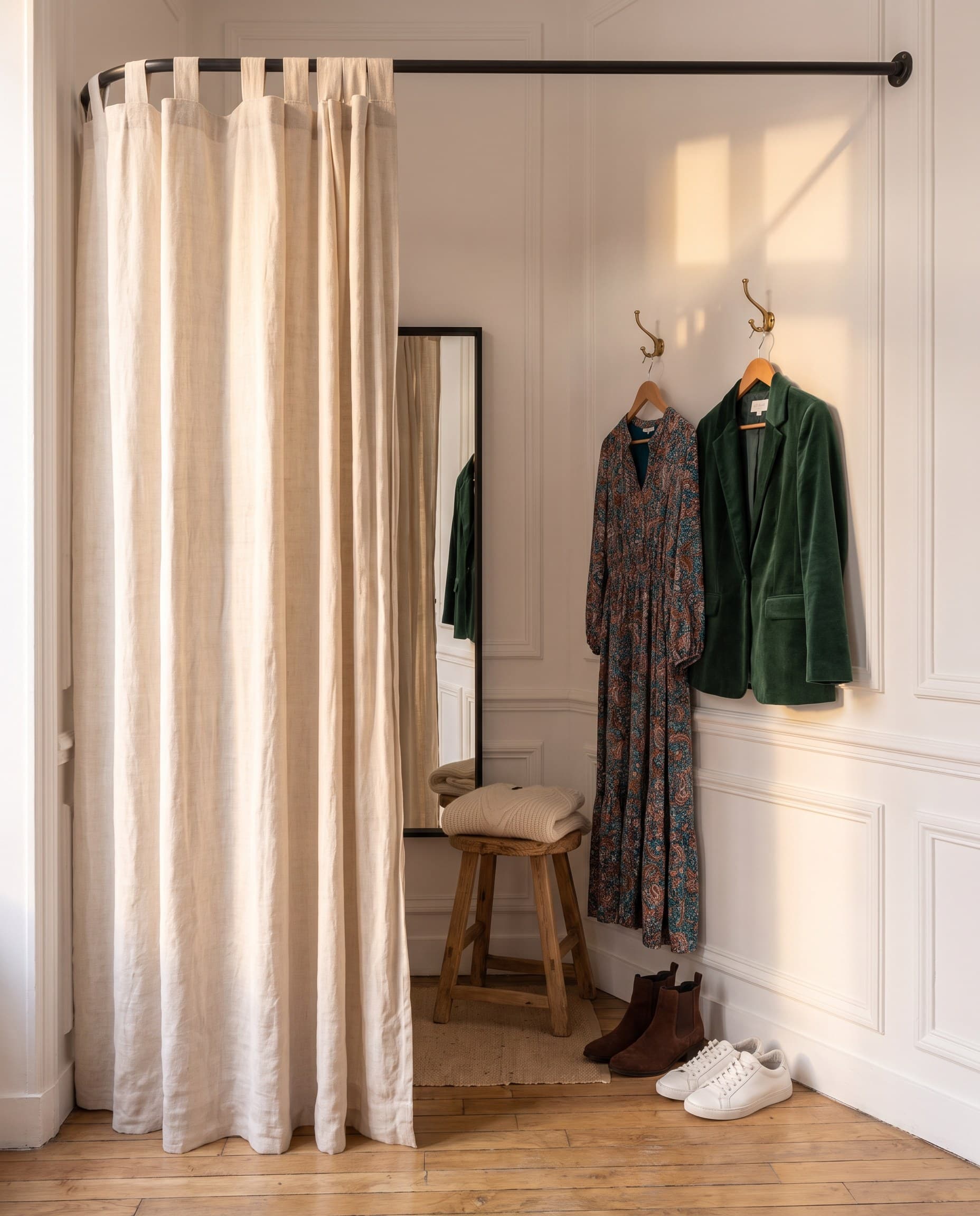 Une cabine d'essayage au rideau de lin, des tenues accrochées à côté